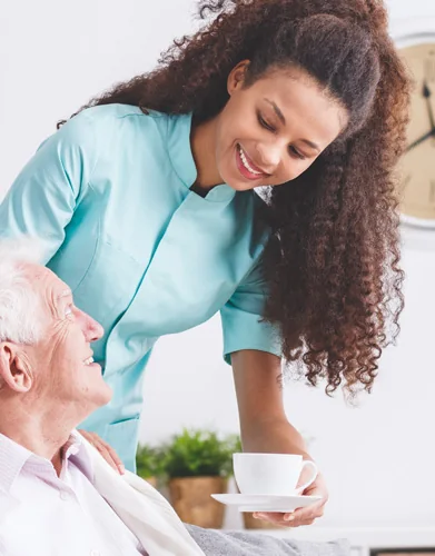 A hospice nurse bringing tea to an older patient at home